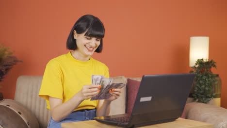 Woman-looking-at-laptop-counting-money.
